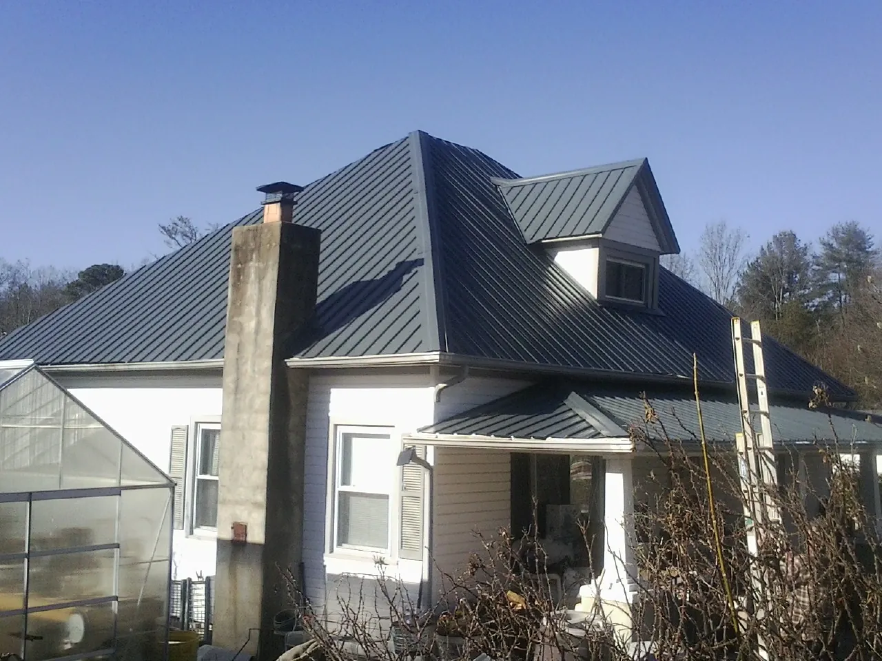 Dark blue standing seam metal roof on a white farmhouse with dormer — Slate & Tile Roof Repair by Roofing Brothers in Parker Ford