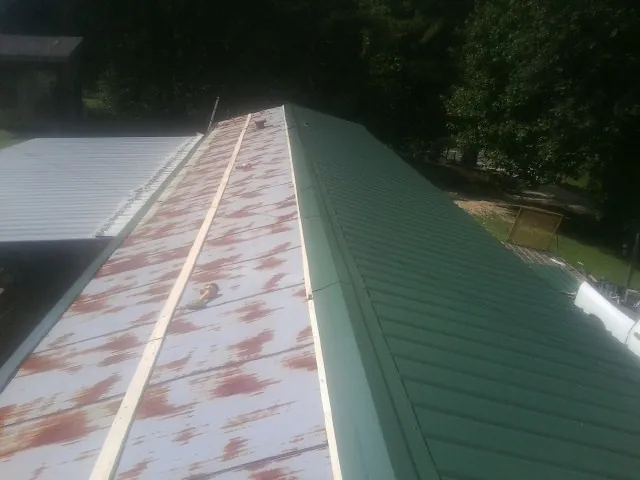 Old rusted panels beside newly installed green metal roofing — Wind Damage Roof Repair by Roofing Brothers in Parker Ford