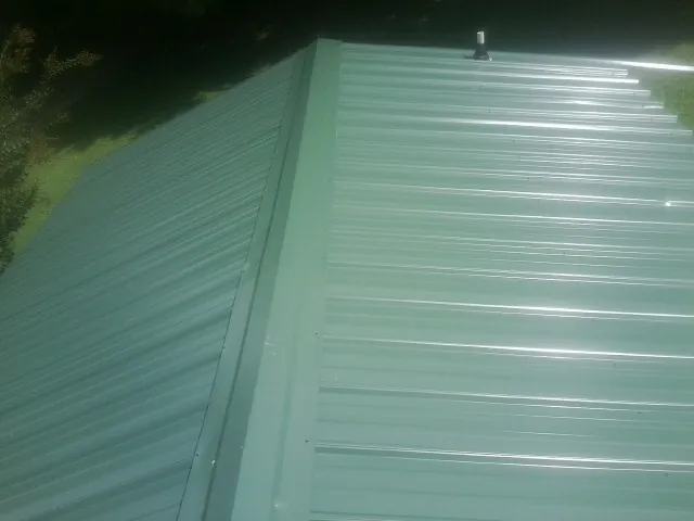 New green metal panels meeting at the ridge of a roof — Flat Roof Repair work by our crew in Parker Ford