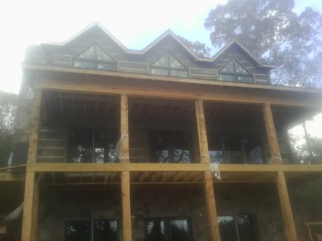 Dormers and porch framing on a large log home under construction — Roof Coating work by our crew in Parker Ford