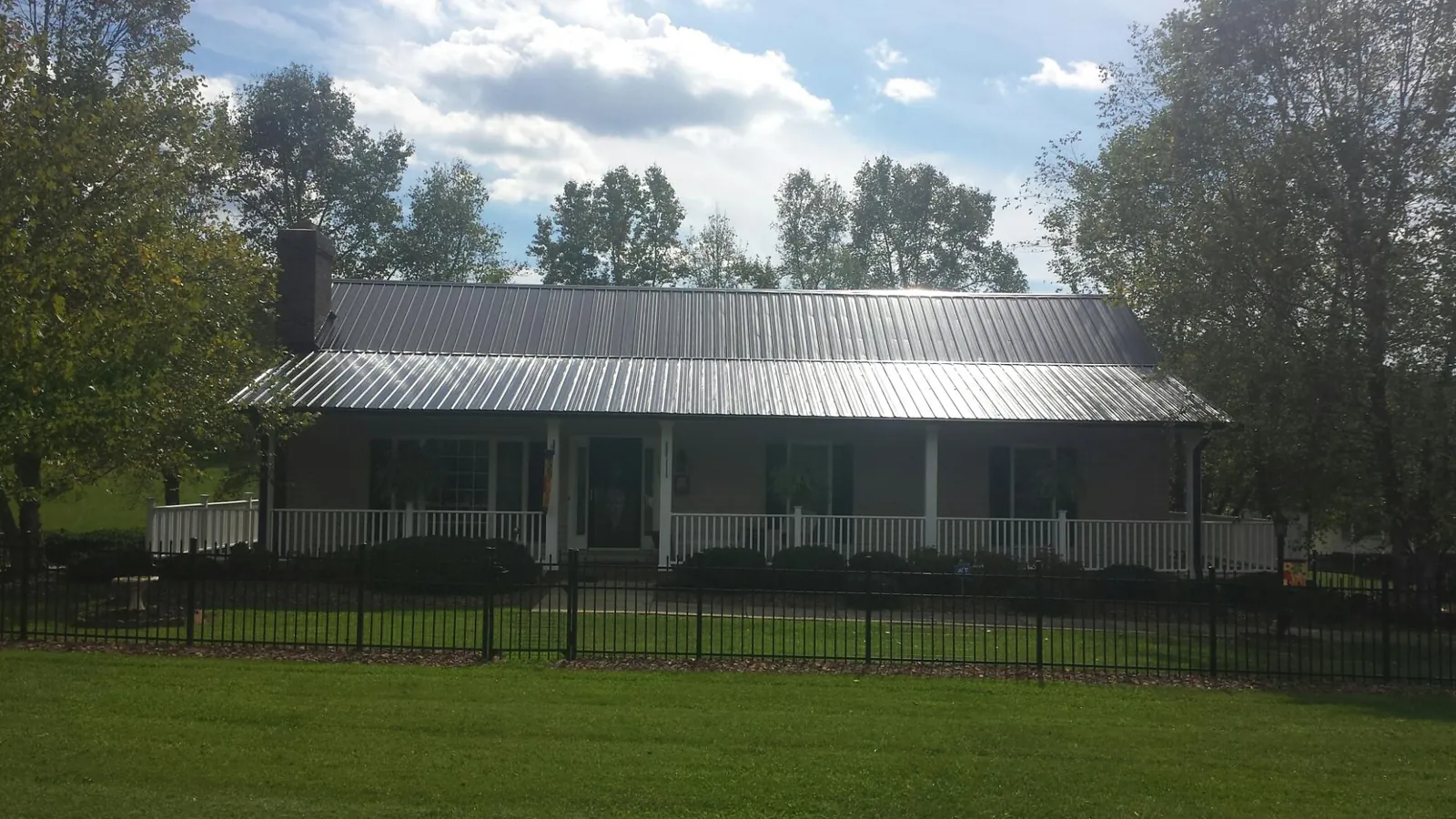 Gray metal roof on a brick ranch with a full width front porch — Gutter Guard Installation work by our crew in Parker Ford