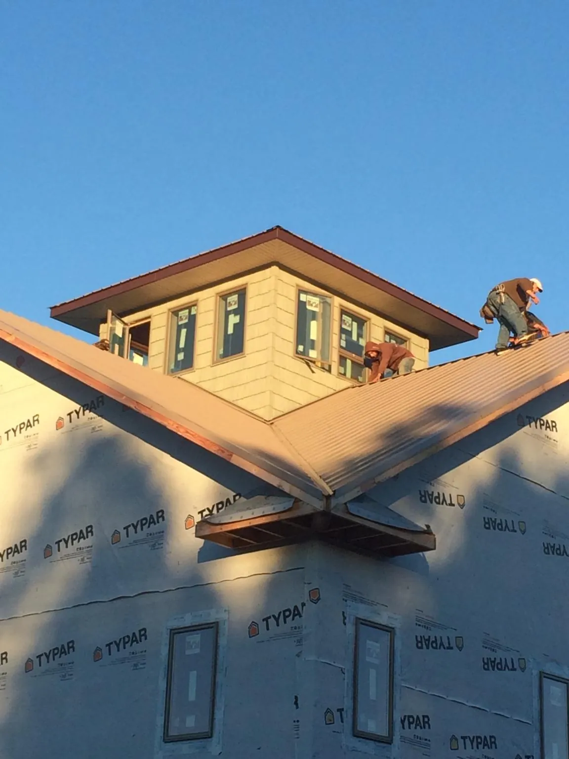 Roofers working around a rooftop cupola on a new metal roof at sunset in Parker Ford